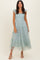woman wearing a light blue tiered midi dress with ruffled straps and polka dot fabric.