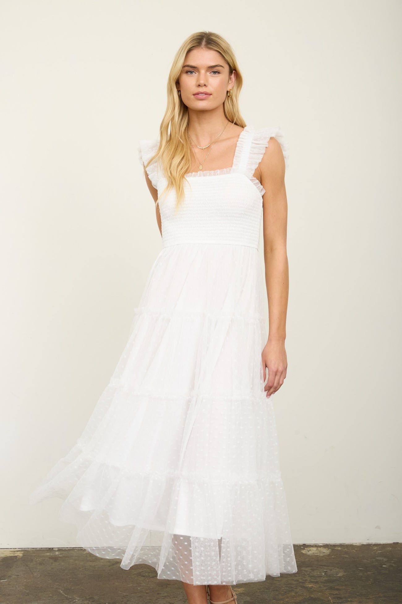 woman wearing a white tiered midi dress with ruffled straps and a smocked bodice