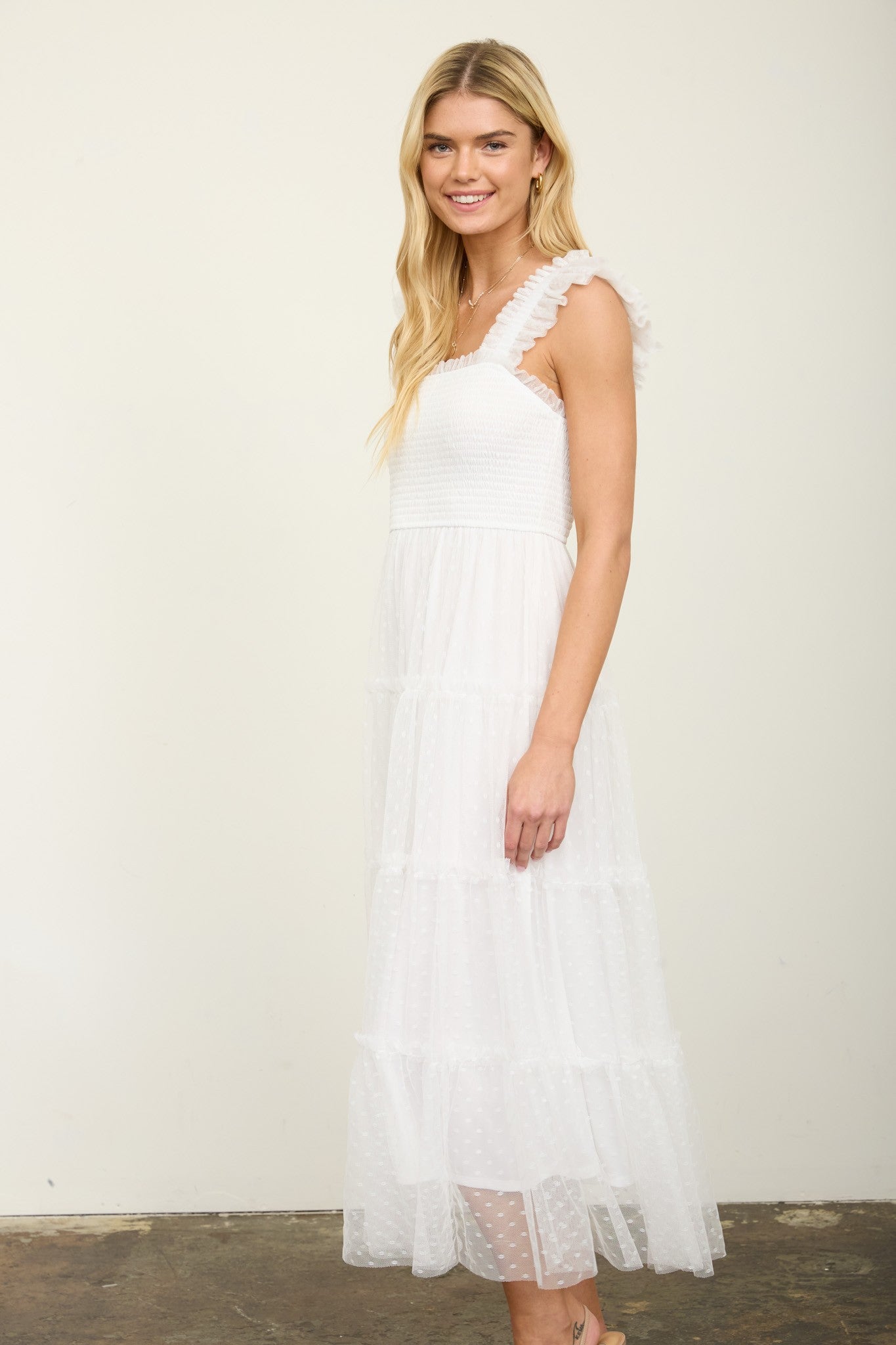 woman wearing a white tiered maxi dress with textured detailing and ruffled straps