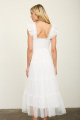 woman wearing a white tiered midi dress with ruffled sleeves and a smocked bodice, seen from the back