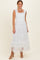 woman wearing a white tiered maxi dress with ruffled straps and a smocked bodice, standing and smiling