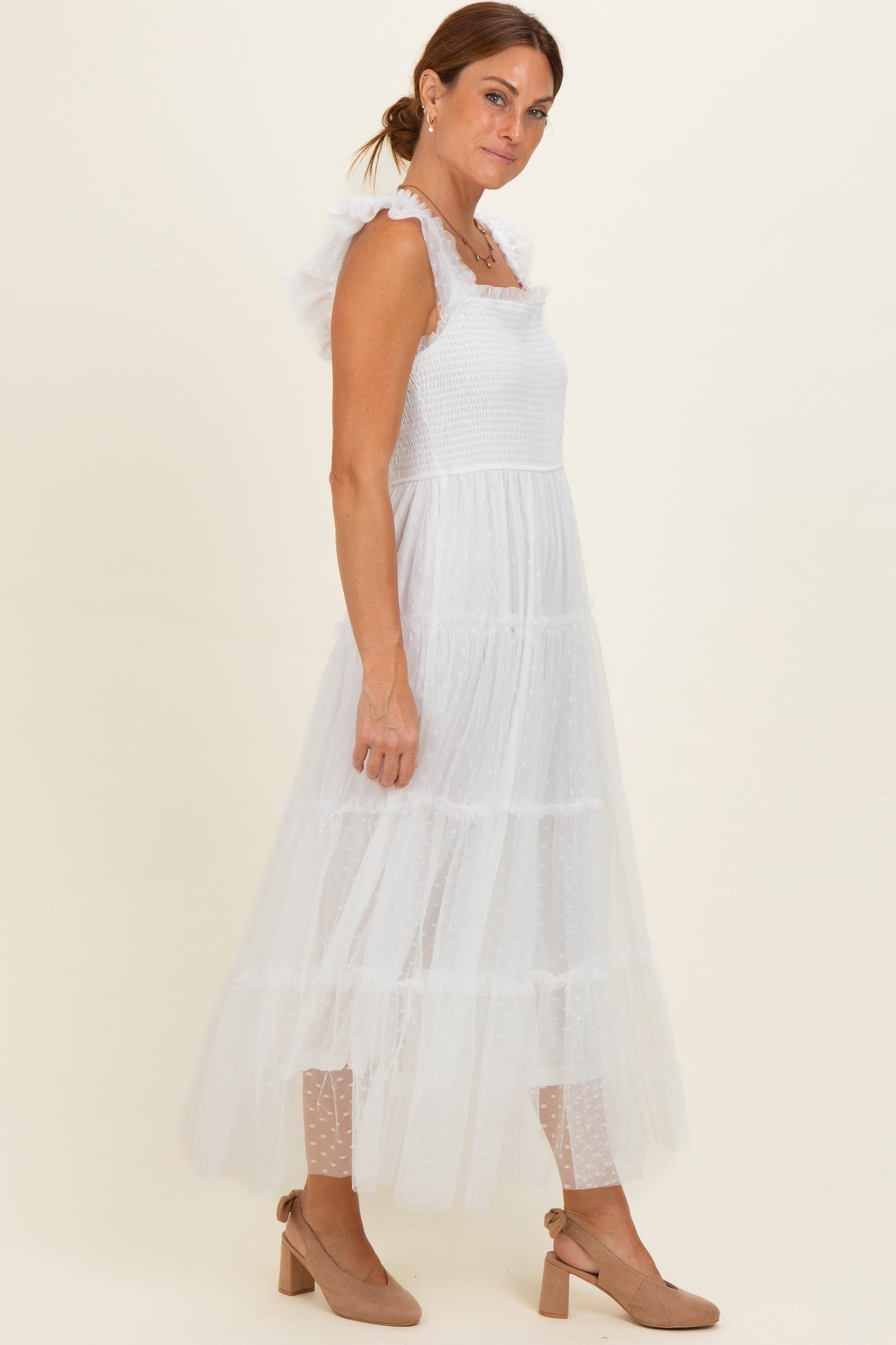 woman wearing a white tiered maxi dress with ruffled straps and polka dot details