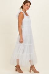 woman wearing a white tiered maxi dress with ruffled straps and polka dot details