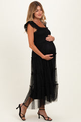 woman wearing a black polka dot maternity maxi dress with ruffled straps and crinkled tiers, holding her baby bump