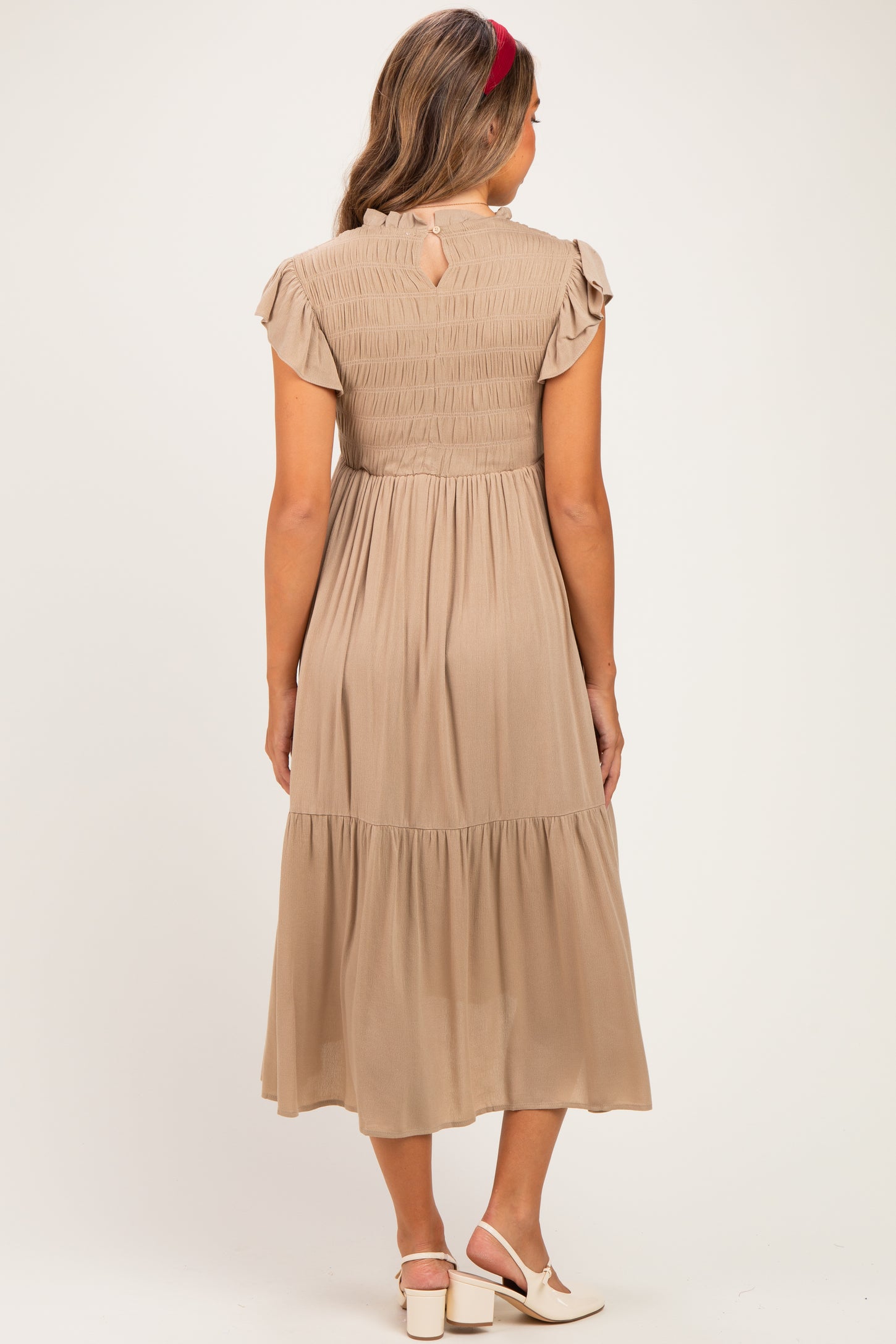 woman wearing a beige maternity dress with flutter sleeves and a tiered skirt, showing the back view