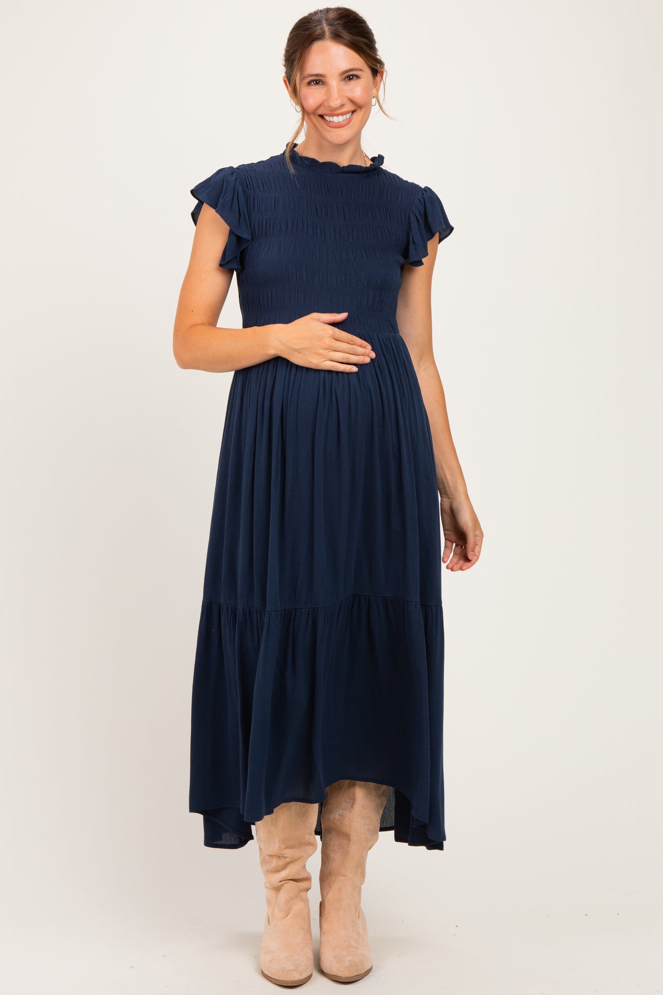 woman wearing a navy blue maternity maxi dress with short ruffled sleeves and a smocked bodice, showing her baby bump
