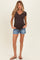 woman wearing a dark brown short sleeve maternity top with buttons and denim shorts, showing her baby bump