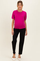 woman wearing a hot pink short sleeve maternity top and black pants, with a visible baby bump