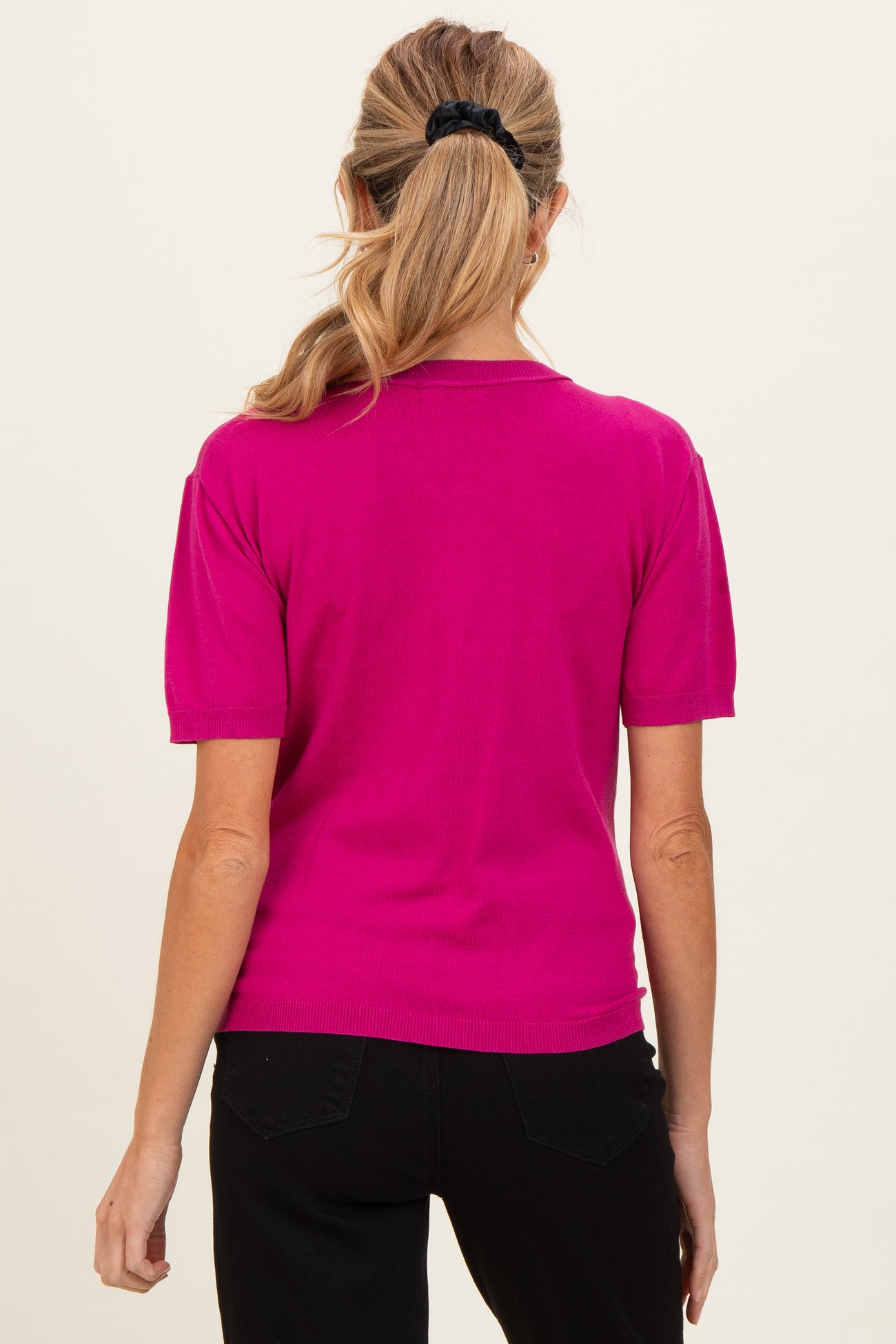 woman wearing a bright pink short sleeve maternity top, viewed from the back