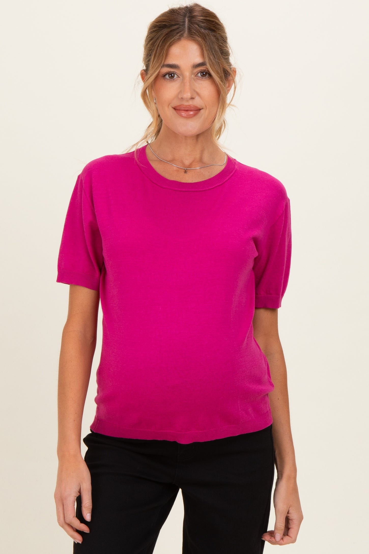 woman wearing a bright pink short sleeve maternity top with a relaxed fit and visible baby bump