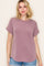 woman wearing a mauve short sleeve top with rolled cuffs and a relaxed fit, paired with denim shorts