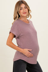 woman wearing a mauve short sleeve maternity top and holding her baby bump