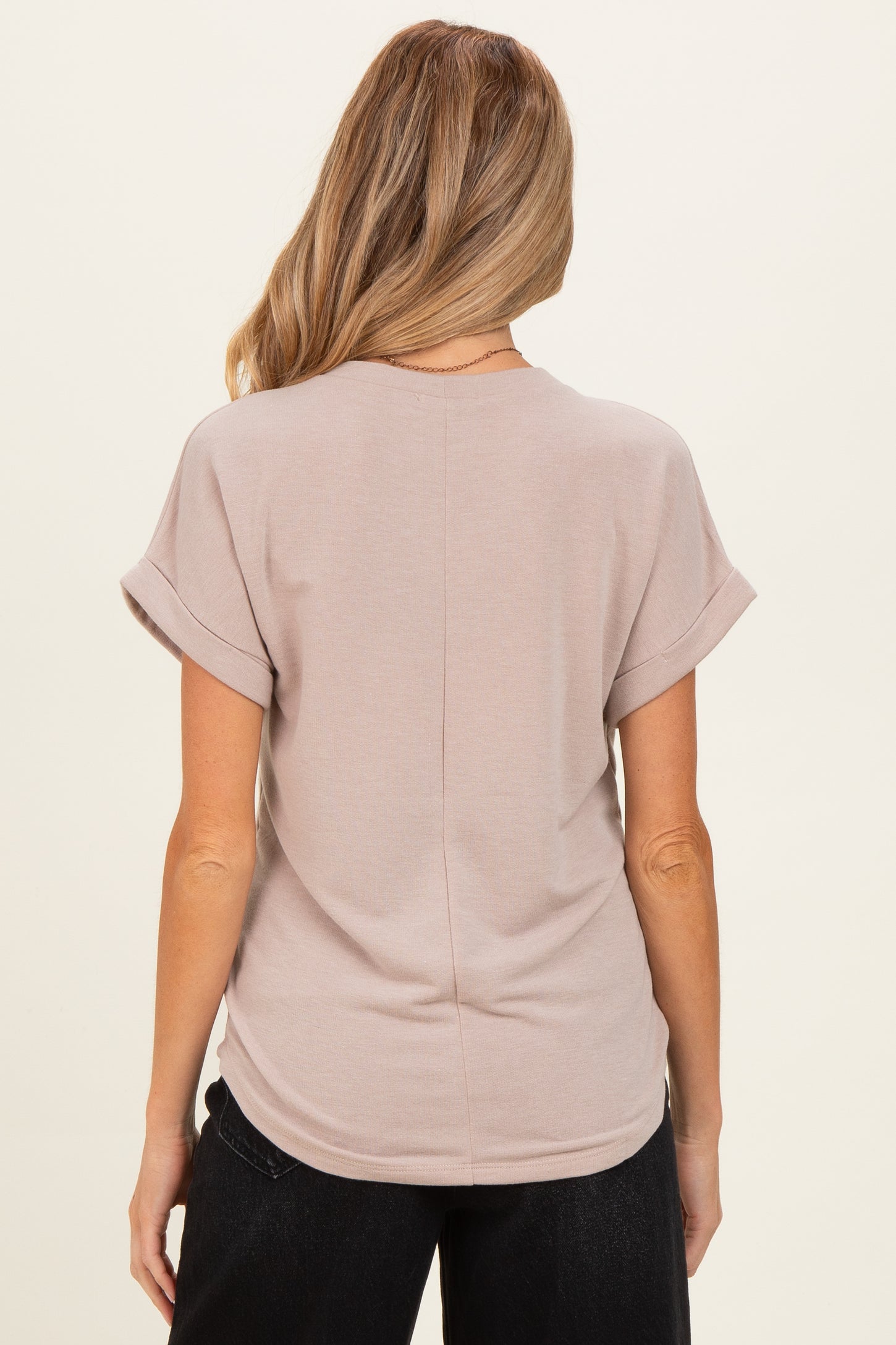 woman wearing a taupe short sleeve maternity top with rolled sleeves, showing the back view