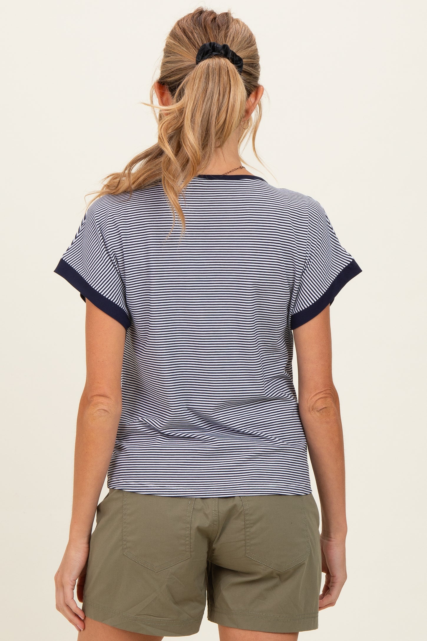 woman wearing a navy and white striped maternity top, viewed from the back with casual green shorts