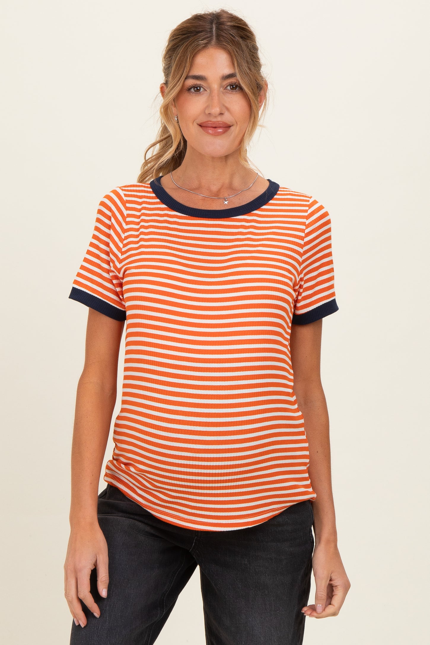 woman wearing an orange and white striped maternity top with navy blue trim and a visible baby bump