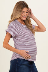 woman wearing a striped maternity top in shades of purple and white, holding her baby bump while smiling