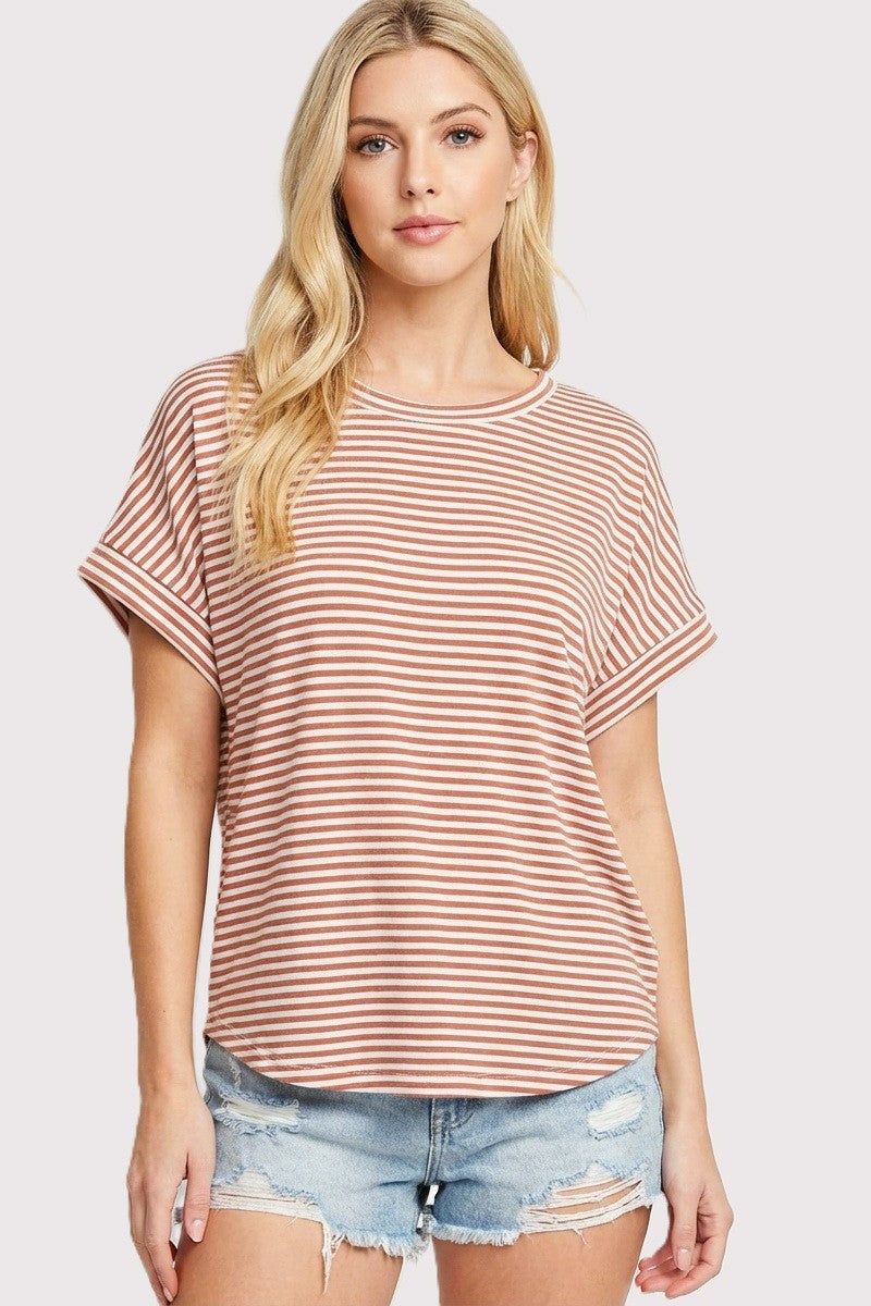 woman wearing a coral and white striped short sleeve top with rolled sleeves and distressed denim shorts