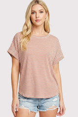 woman wearing a coral and white striped short sleeve top with rolled sleeves and distressed denim shorts