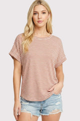woman wearing a rust and ivory striped short sleeve top paired with distressed denim shorts