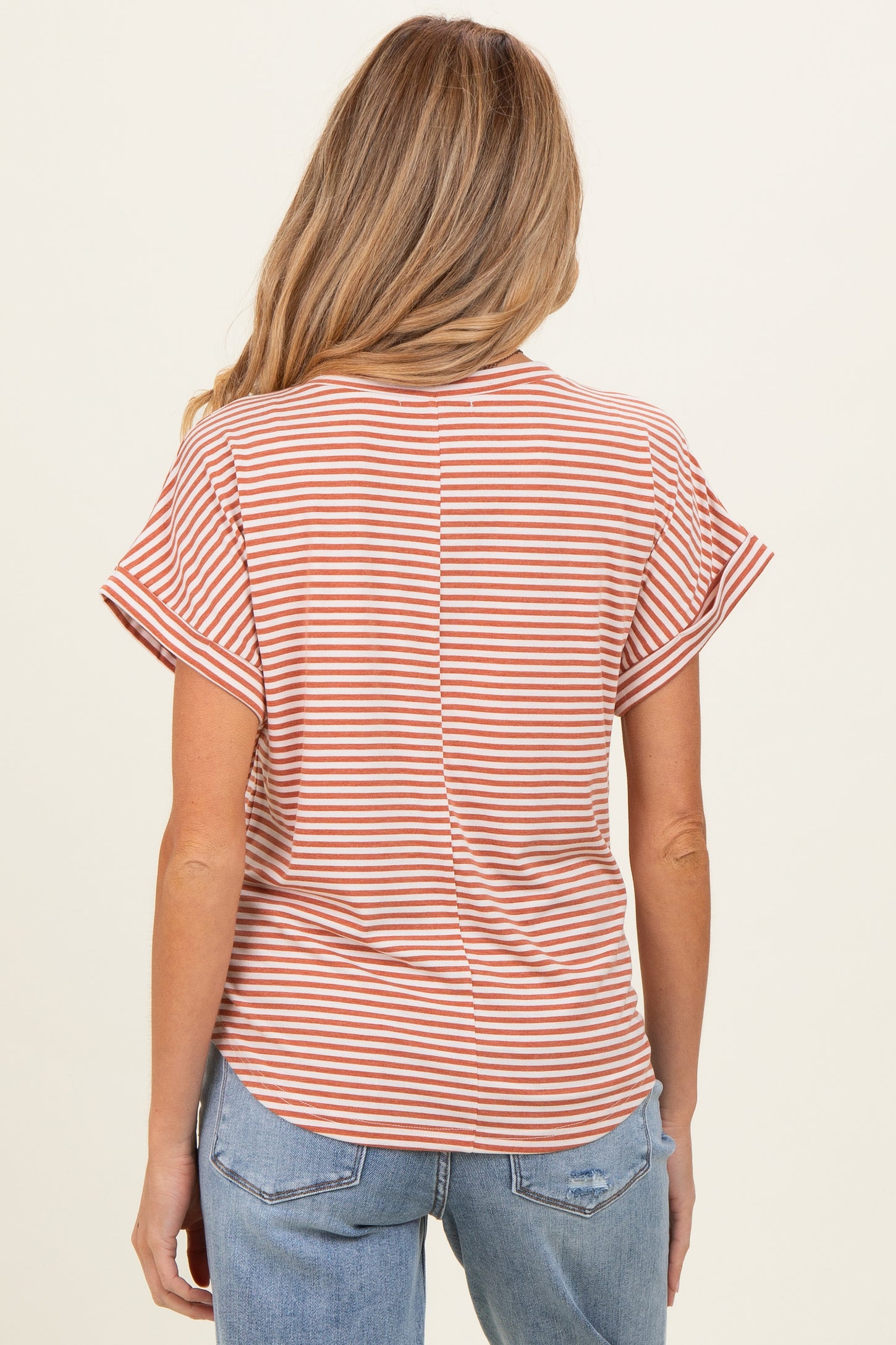 woman wearing a rust and white striped maternity top with short sleeves and a relaxed fit, viewed from the back