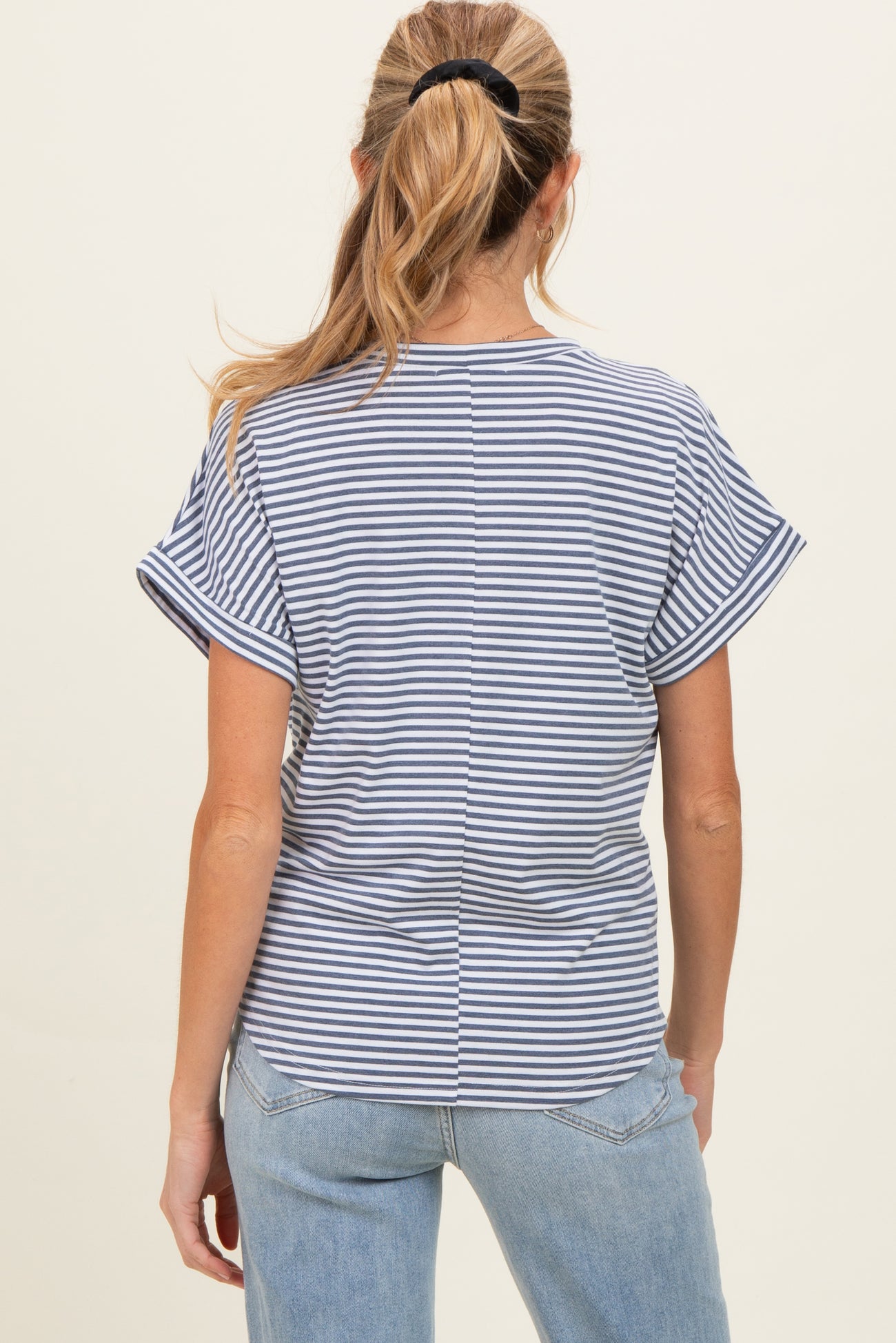 woman wearing a navy and white striped short sleeve maternity top, seen from the back with casual jeans
