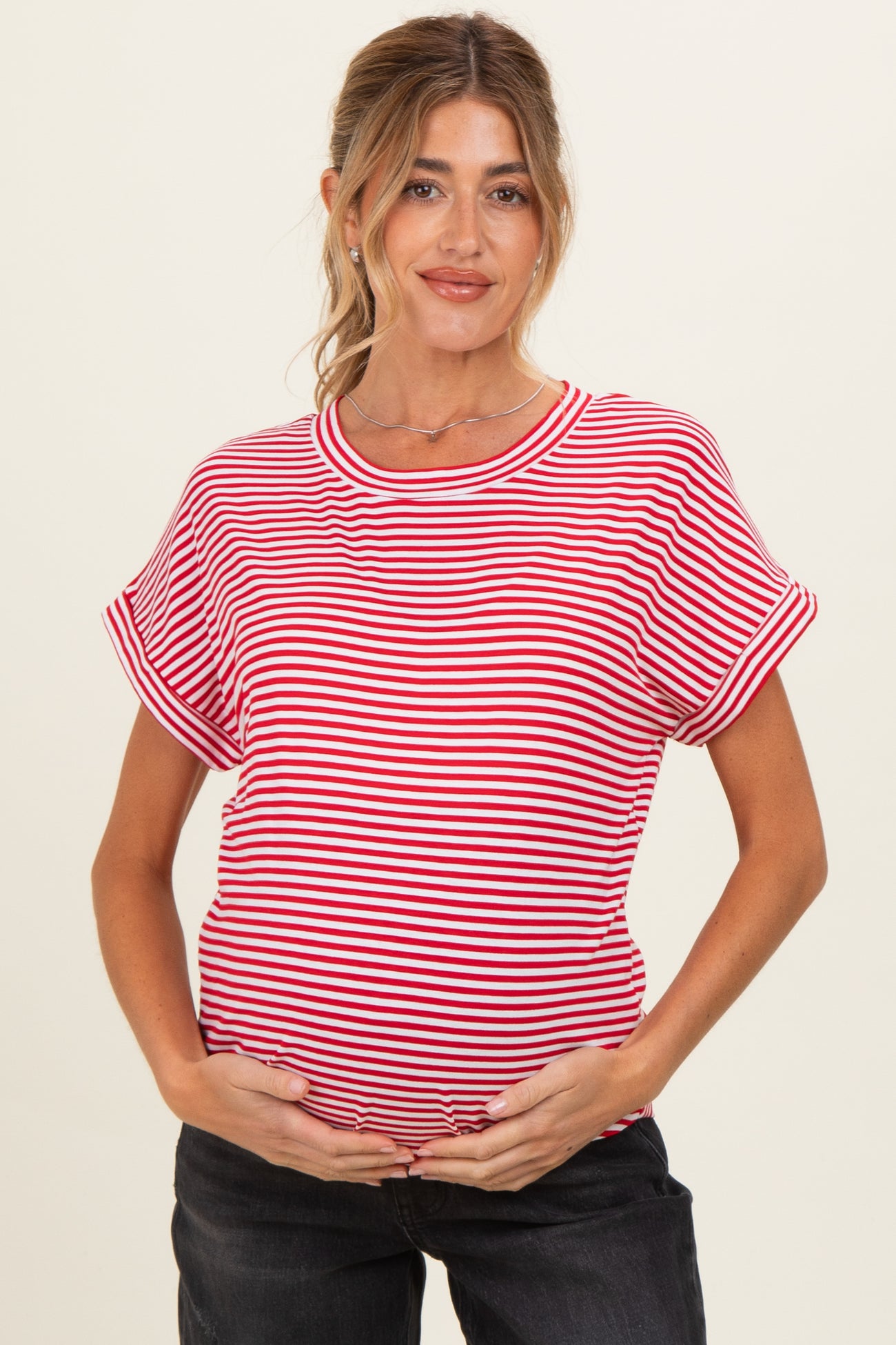 woman wearing a red and white striped maternity top and holding her baby bump