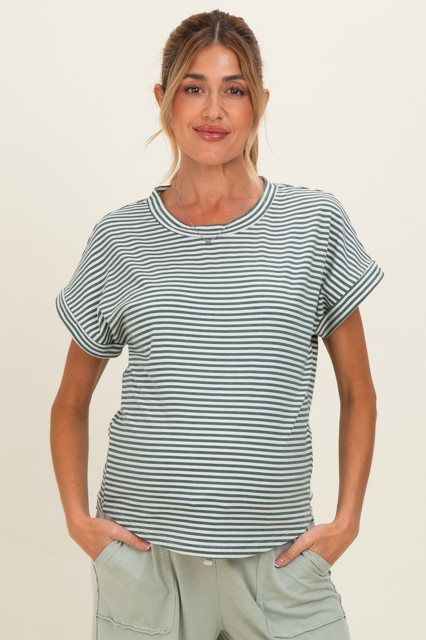 woman wearing a green and white striped maternity t-shirt with rolled sleeves and relaxed fit, holding her baby bump