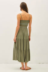 woman wearing an olive green tiered maxi dress with a smocked bodice and thin straps seen from the back