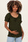 woman wearing a dark green maternity top with short puff sleeves, holding her baby bump
