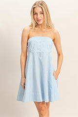woman wearing a light blue striped strapless sundress with pockets