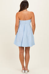 woman wearing a light blue striped strapless maternity dress with a fitted bodice and flowing skirt