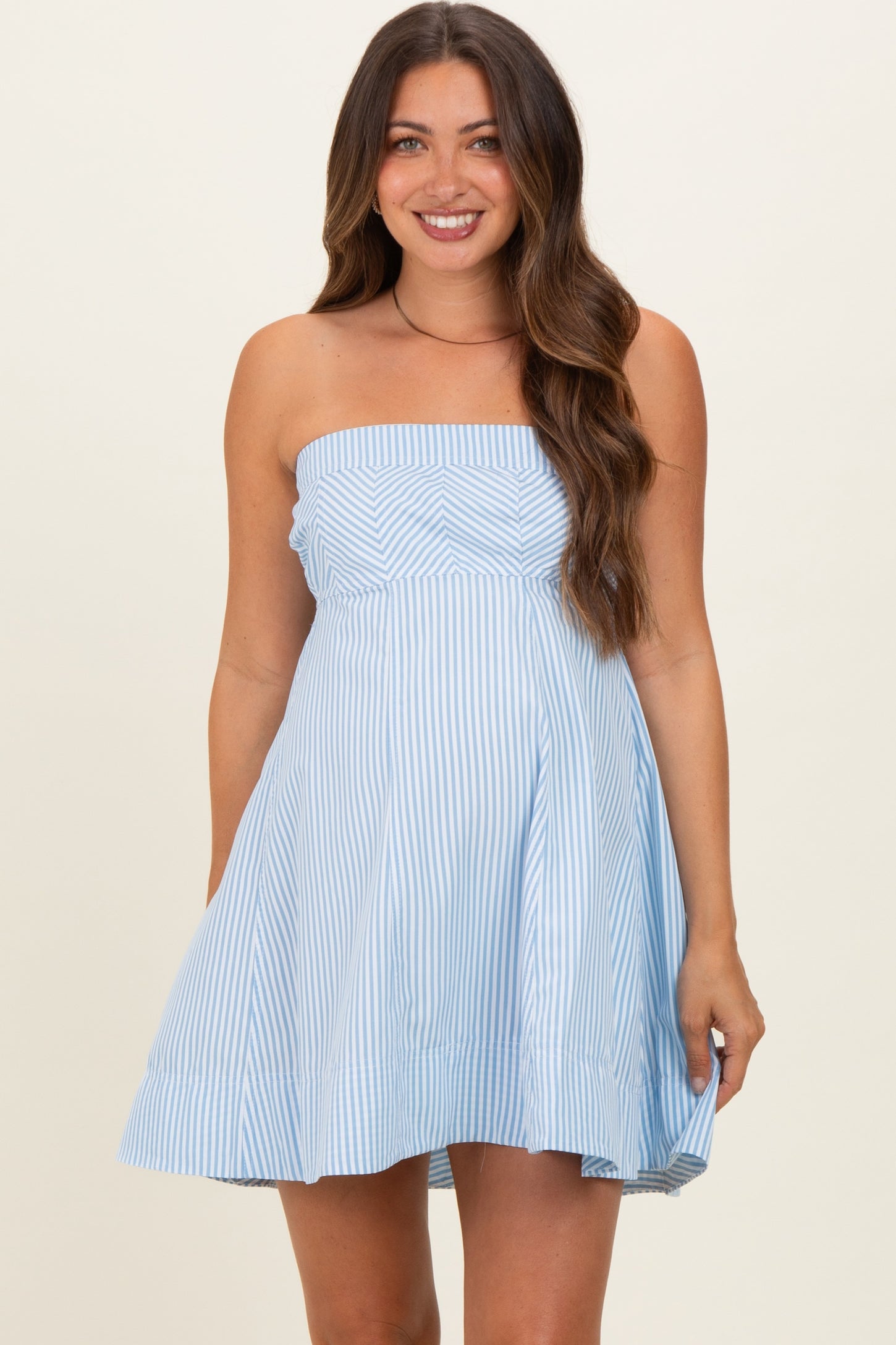 woman wearing a light blue striped strapless maternity dress, showing her baby bump
