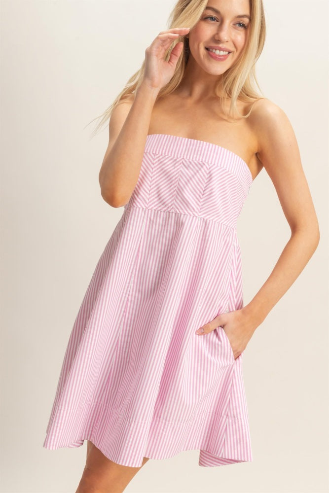 woman wearing a pink and white striped strapless dress with a gathered bodice and pockets