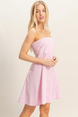 woman wearing a pink and white striped strapless dress with a fitted bodice and flared skirt
