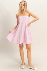 woman wearing a pink and white striped strapless sundress with pockets