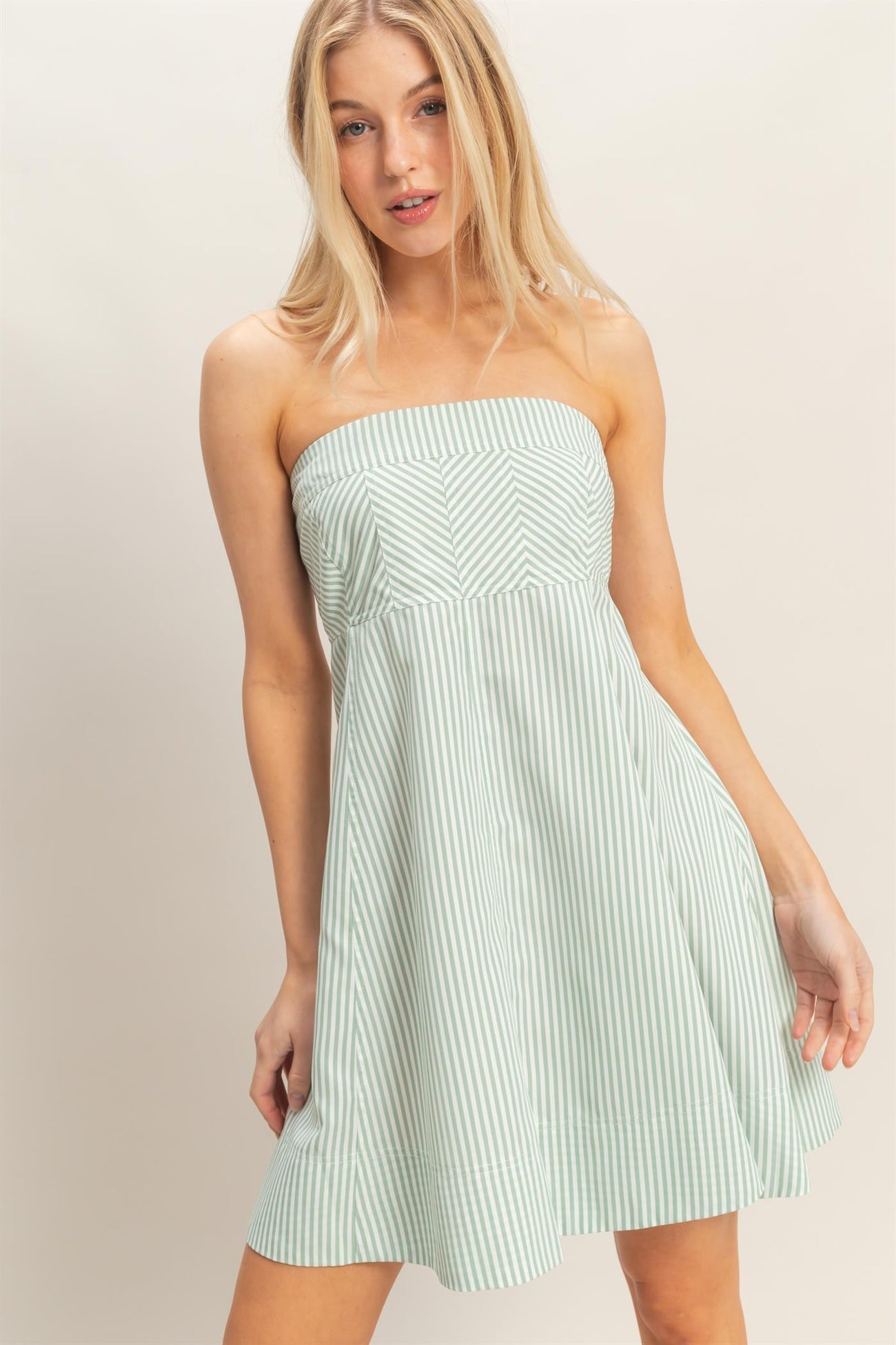 woman wearing a striped green strapless dress with a flared skirt