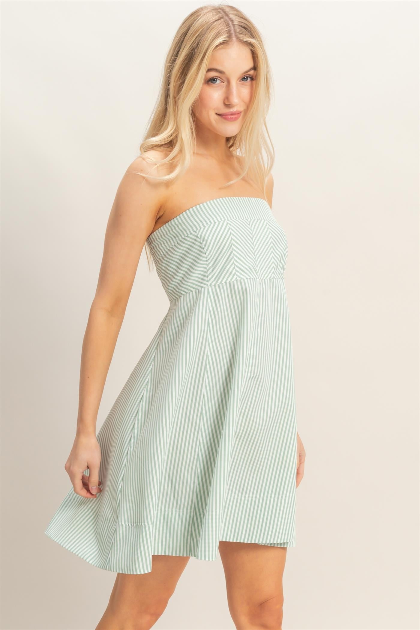 woman wearing a green and white striped strapless dress with a fitted bodice and flared skirt