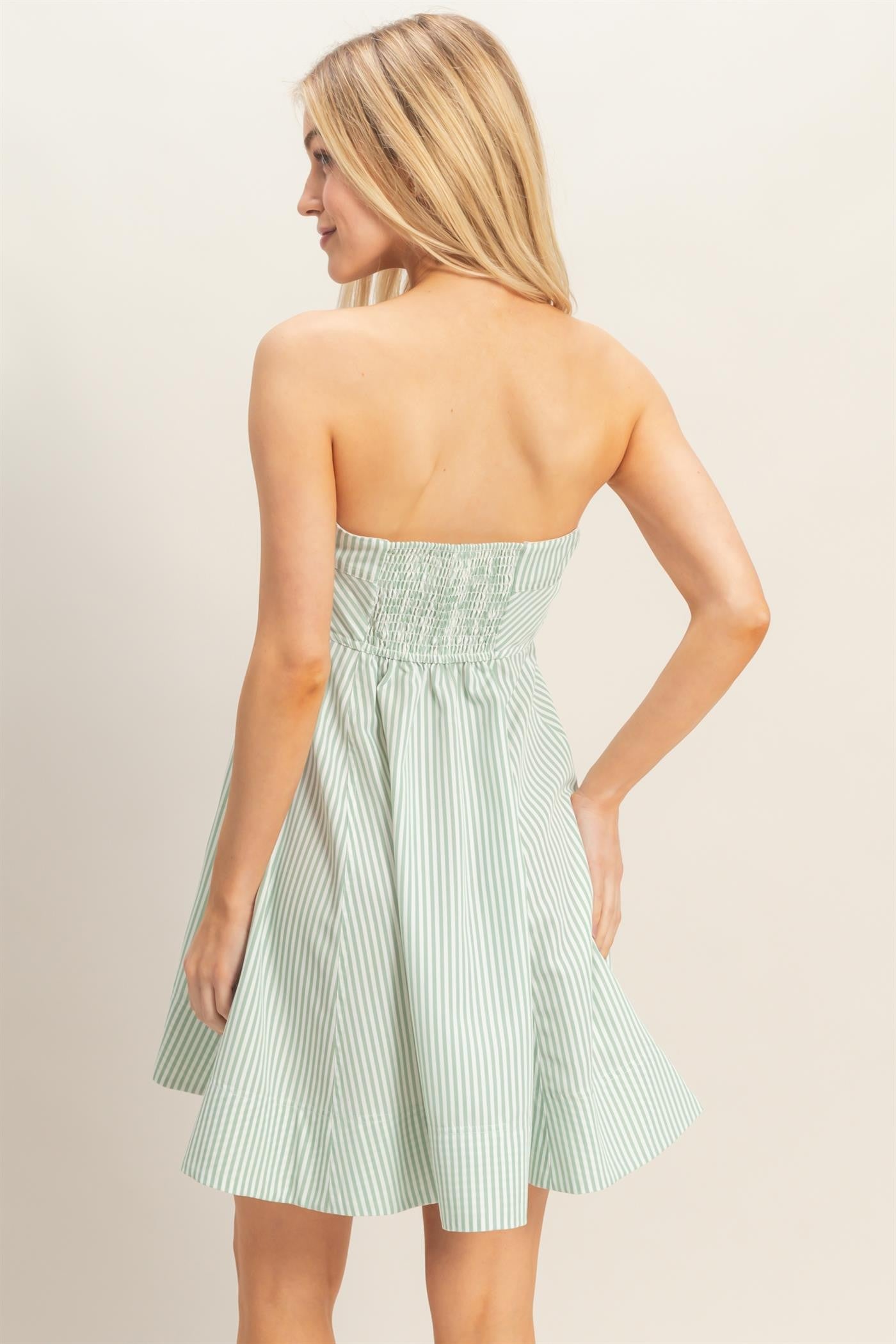 woman wearing a sleeveless green and white striped sundress with a smocked bodice and flared skirt