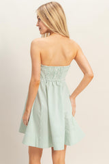 woman wearing a sleeveless green and white striped sundress with a smocked bodice and flared skirt