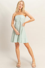 woman wearing a green and white striped strapless sundress with a fitted bodice and flared skirt
