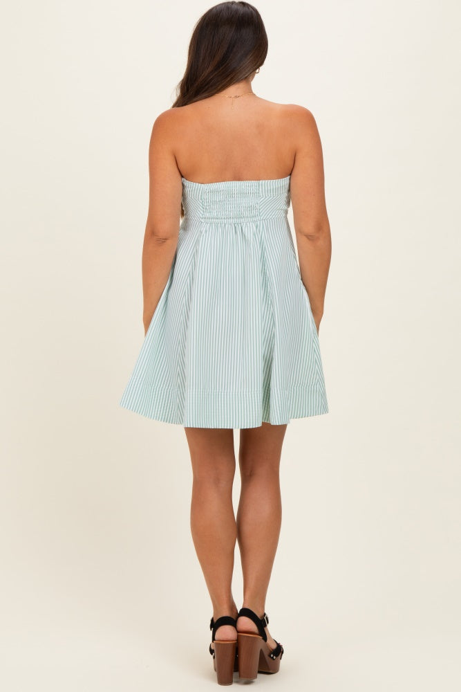 woman wearing a strapless light green and white striped maternity dress with a smocked bodice and flared skirt