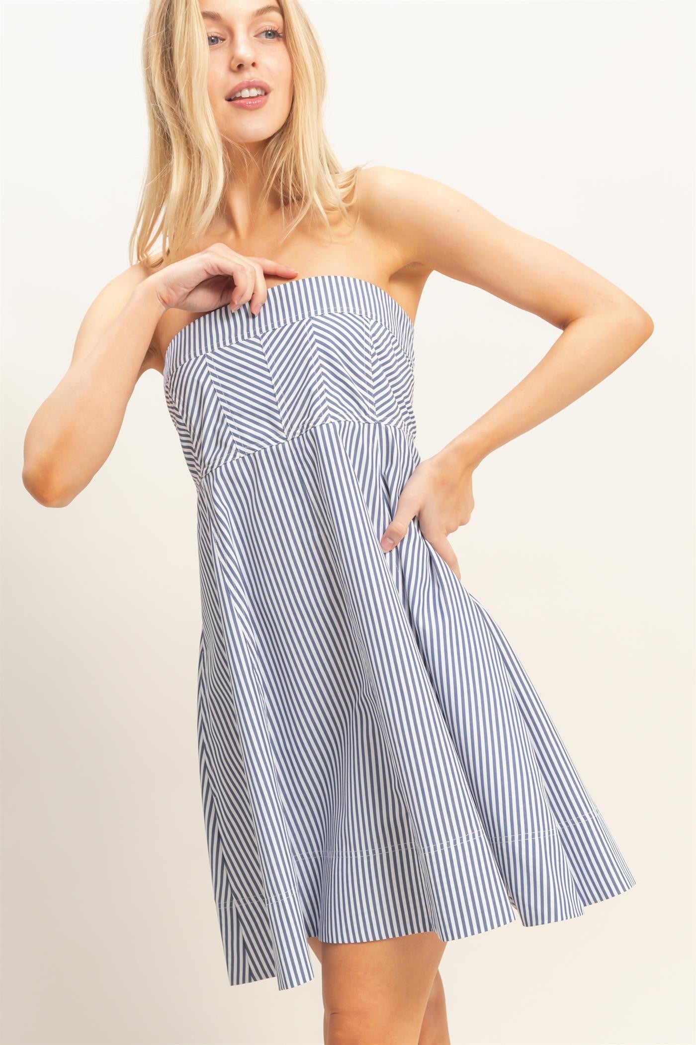 woman wearing a strapless navy and white striped sundress with a flared skirt and pockets