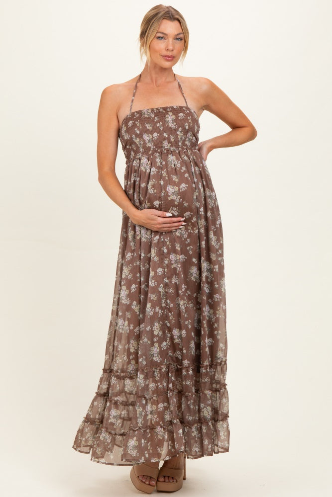woman wearing a brown floral maternity maxi dress, showing her baby bump with a halter neck and tiered skirt