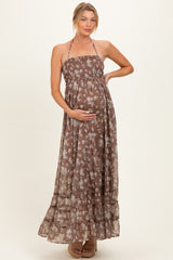 woman wearing a brown floral maternity maxi dress, showing her baby bump with a halter neck and tiered skirt
