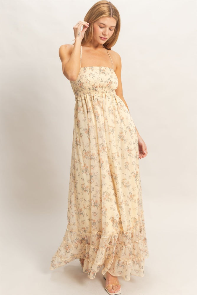 woman wearing a light yellow floral maxi dress with adjustable straps and a flowy skirt