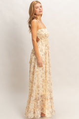 woman wearing a floral maxi dress in soft yellow with a fitted bodice and ruffled hem, posing sideways