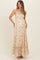 woman wearing a floral light beige maternity maxi dress with an empire waist and ruffled hem, showing her baby bump