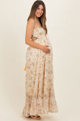 woman wearing a floral maxi maternity dress with cutout details and holding her baby bump