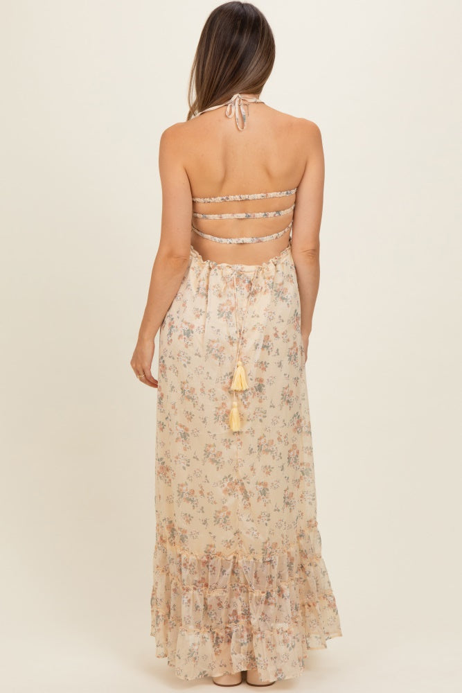 woman wearing a backless floral maternity maxi dress with a tie at the waist and ruffled hem
