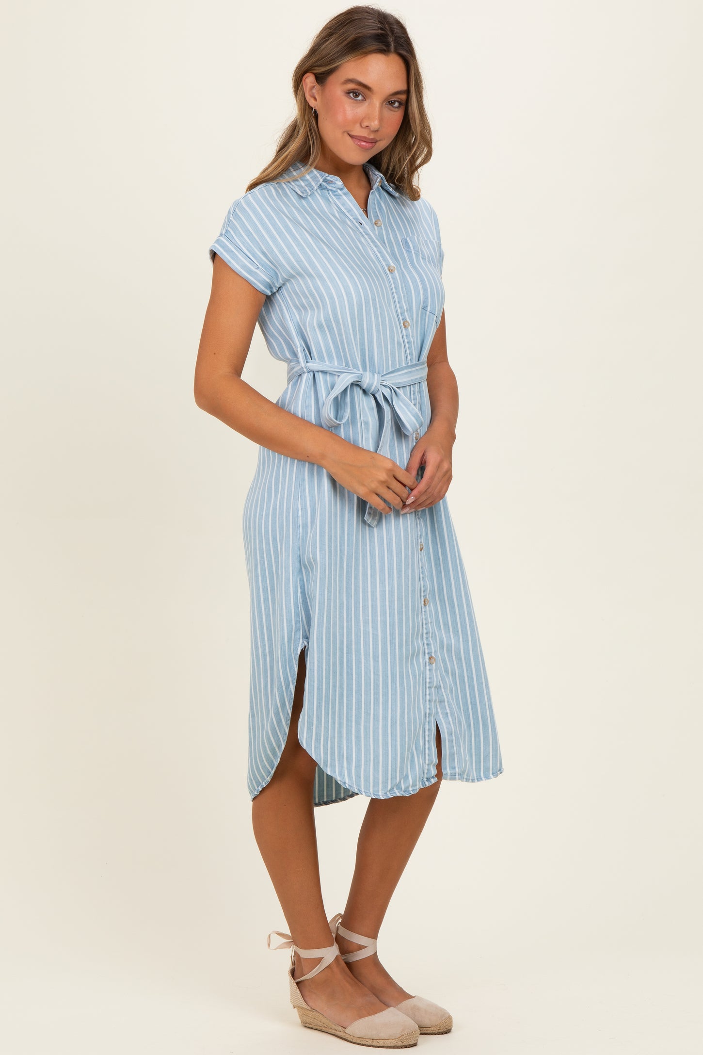 woman wearing a light blue striped midi shirt dress with a belted waist and short sleeves
